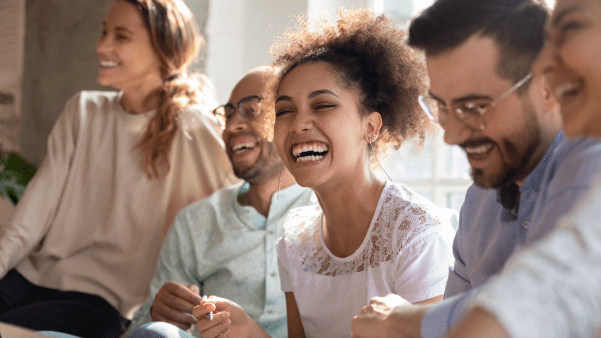 A diverse group of individuals sharing a joyful moment, laughing together in a warm and friendly atmosphere.