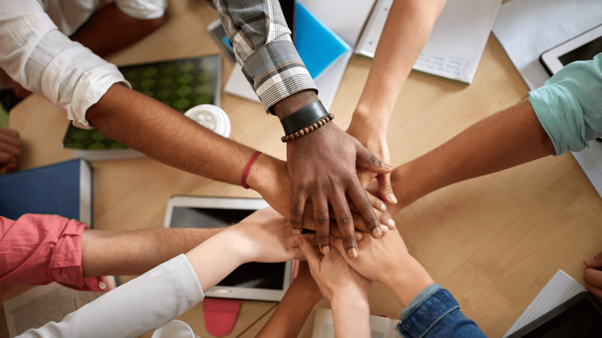 A diverse group of individuals standing together, their hands joined in unity, symbolizing collaboration and togetherness.